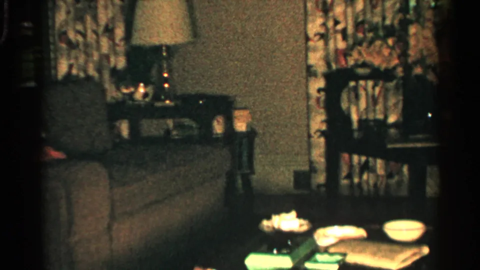 1952 Japan interior frame with a sofa, side-table lamp, wooden chair, patterned curtains, and household items on a low table.