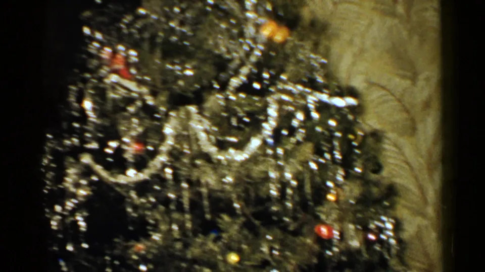 Close 1952 New Hampshire home-movie view of dense silver tinsel, colored ornaments, and tree branches inside a private holiday room.