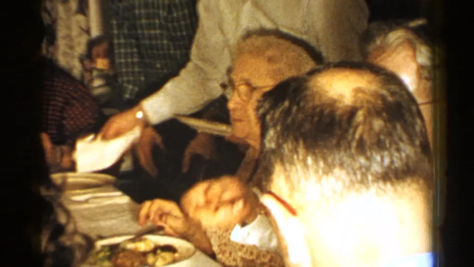 1952 New Hampshire indoor family gathering with adults seated around a dining table, plates of food, and relatives standing nearby.