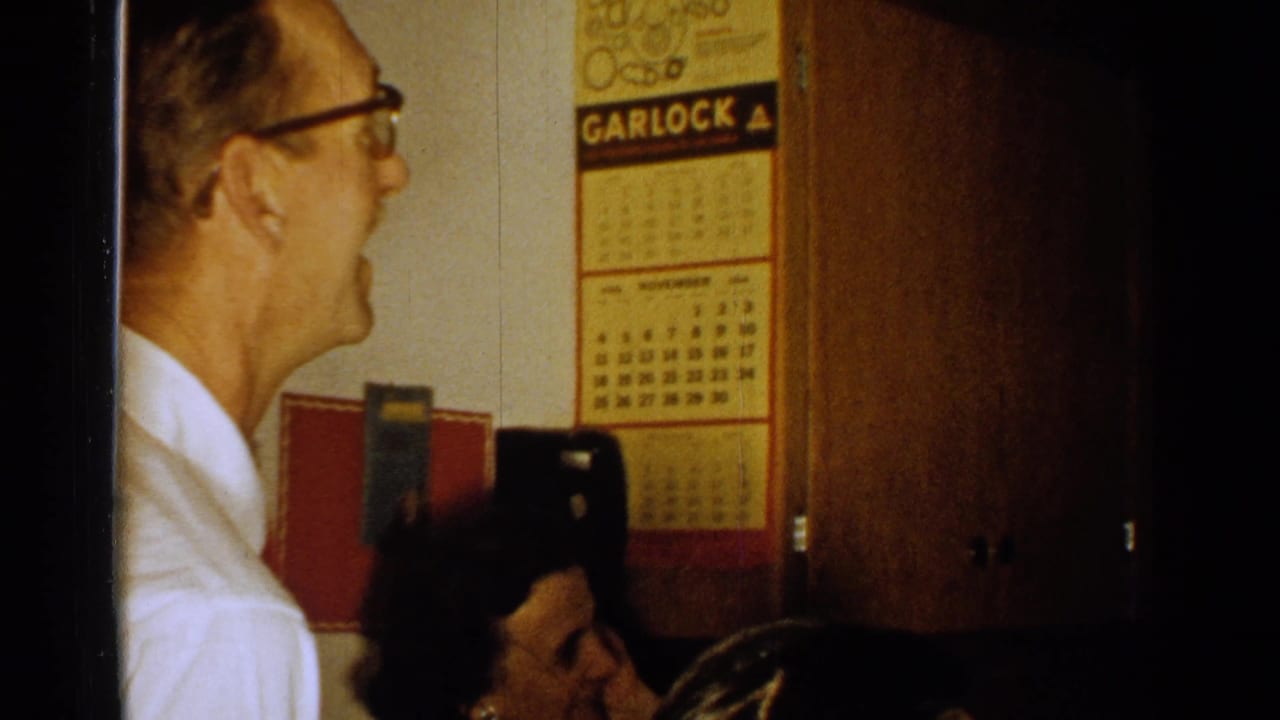 Older man in glasses indoors beside a Garlock wall calendar and dark doorway.