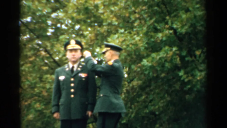 1952 New Hampshire outdoor military ceremony frame with a soldier beside an officer during an apparent medal presentation.