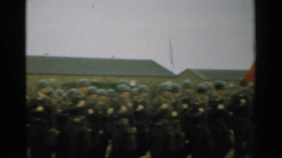 Soft 8mm frame of 1952 New Hampshire soldiers marching close to the camera, with helmets and uniforms filling the lower frame.