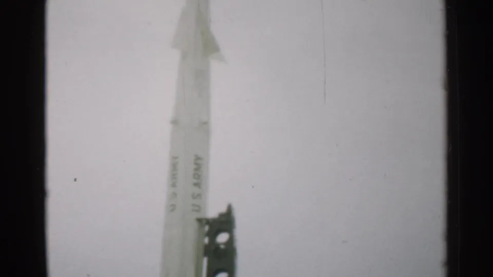 1952 New Hampshire 8mm frame showing the upper portion of a white U.S. Army-marked rocket next to a dark metal launch support.