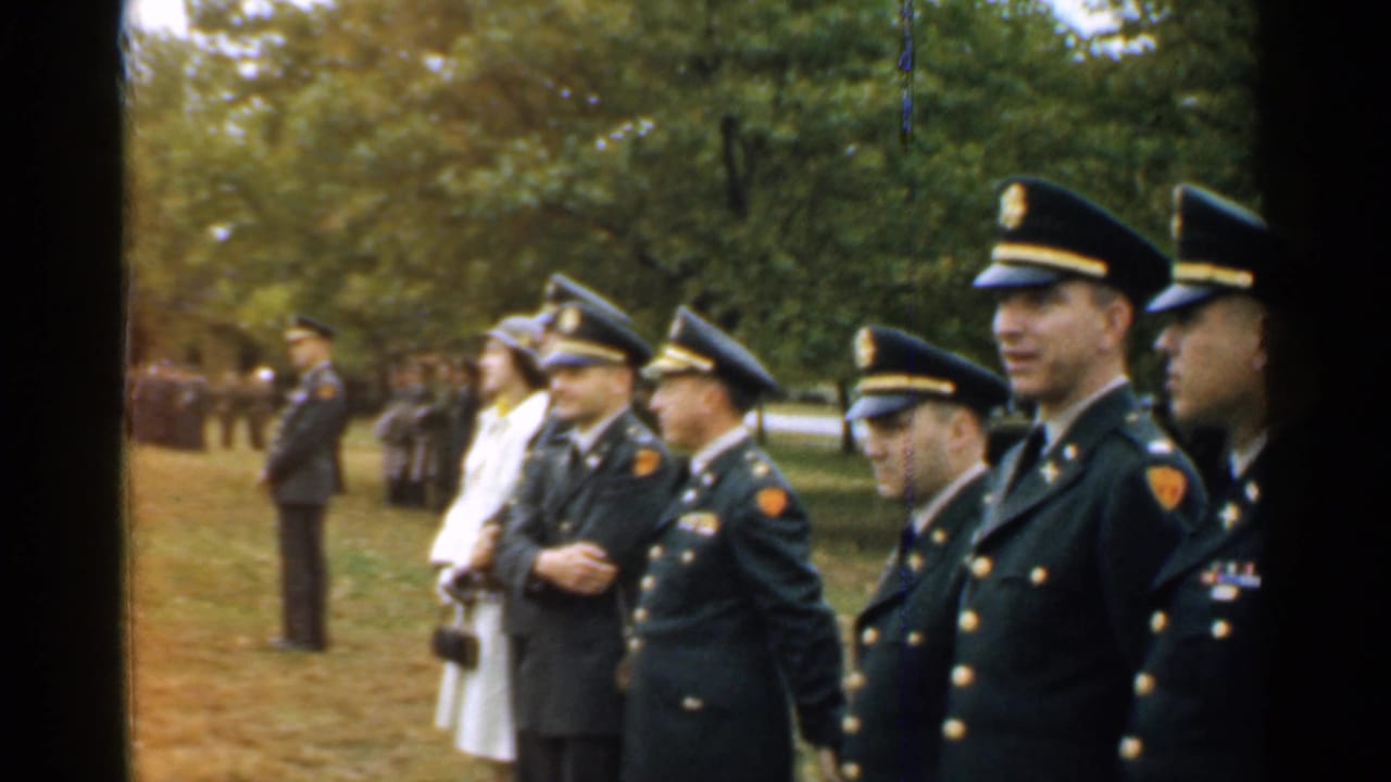 Uniformed officers stand in a park during an outdoor ceremony.