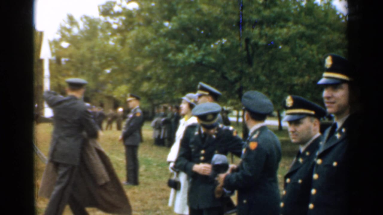 Officers in dark uniforms stand near trees while one person walks past.