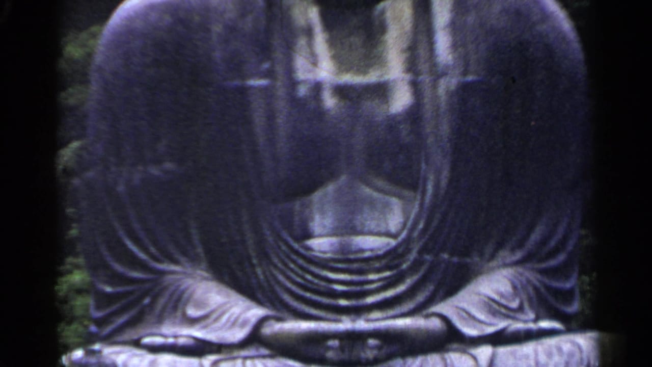 Close view of a seated dark gray Buddha statue with robe folds and hands visible.