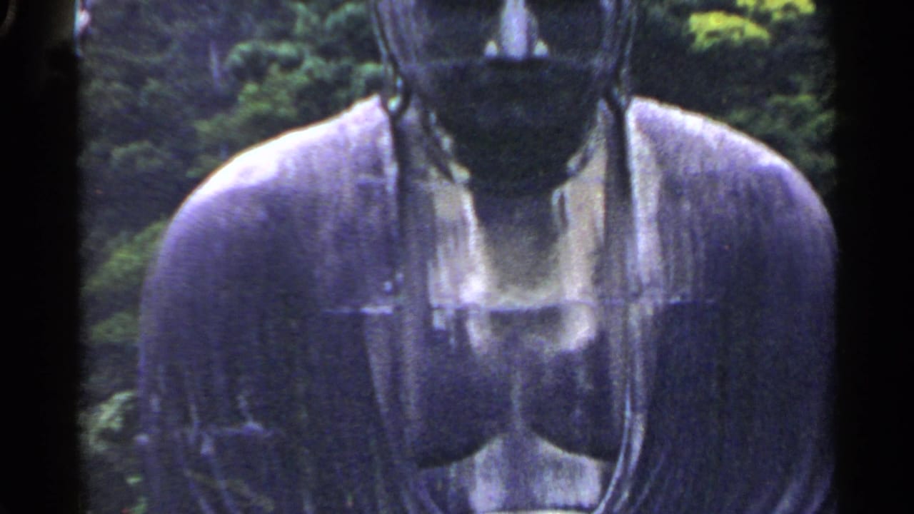 Partial close view of a Buddha statue's upper body against green trees.