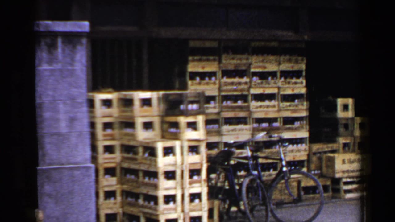 Stacked wooden crates filled with bottles beside a parked bicycle and stone pillar.