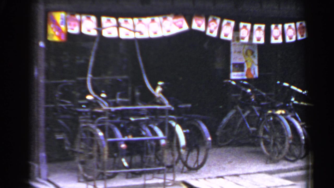 Bicycles parked under an awning with lanterns and Japanese signage at night.