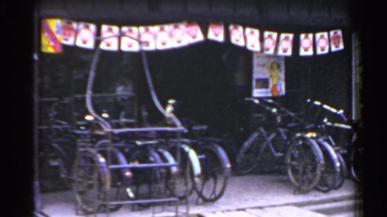 Night storefront with multiple bicycles, lanterns, and posters near the entrance.