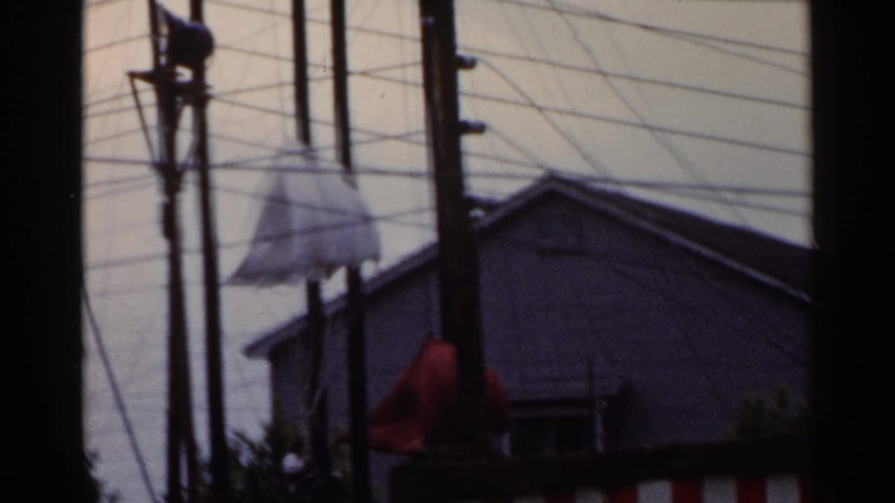 Early 1950s Japan street view with utility poles, overhead wires, a low-rise building, and a small awning or hanging sign.