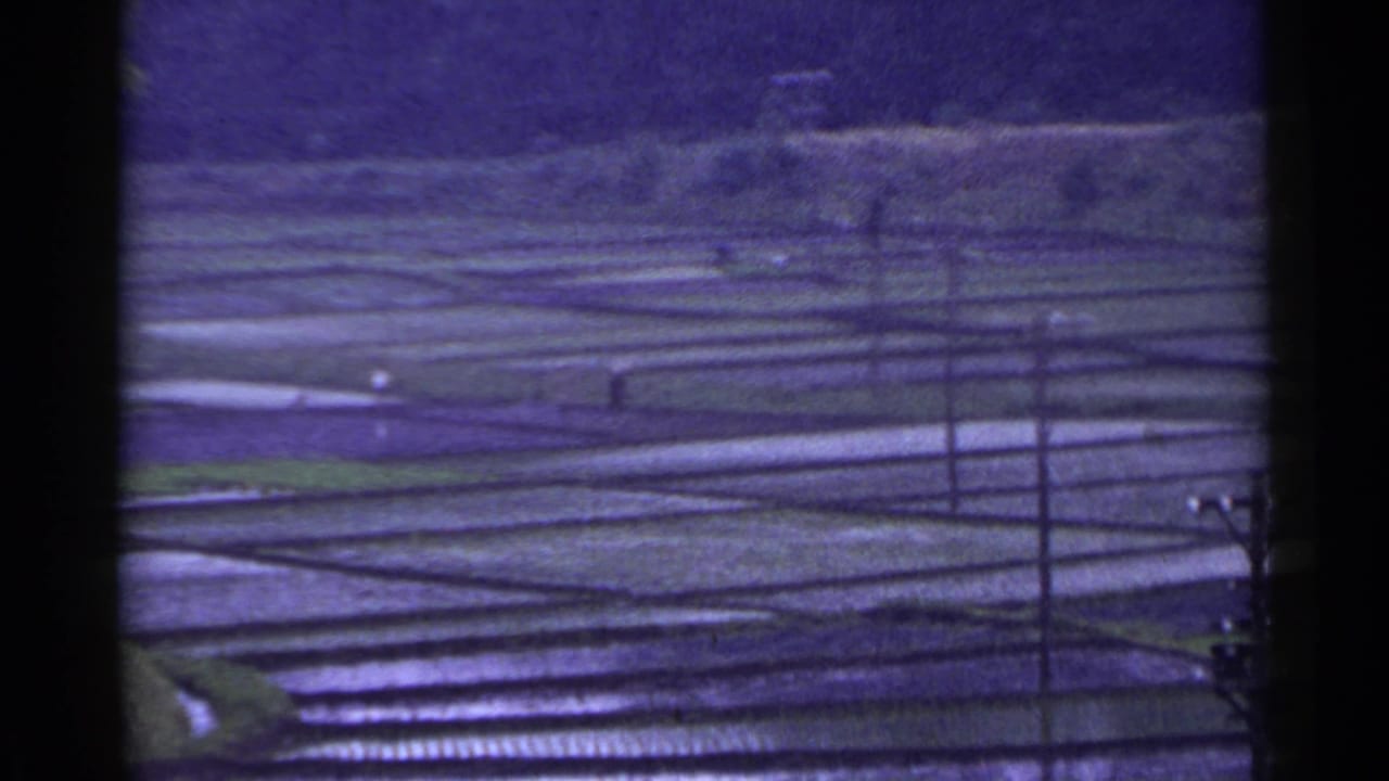 Terraced rice paddies with utility poles and wires viewed from above.