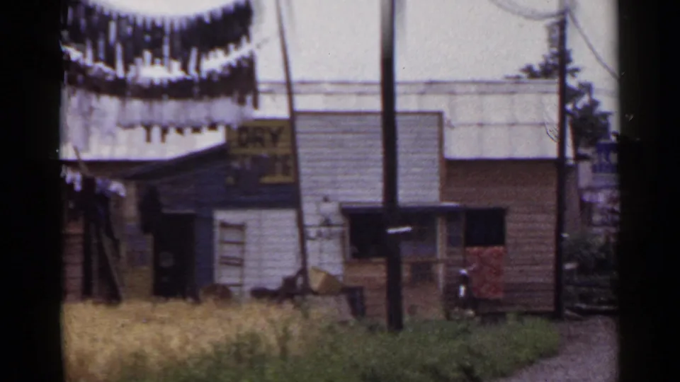 1953 Japan frame with hanging wash, a utility pole, and a small building showing partial dry laundry signage.