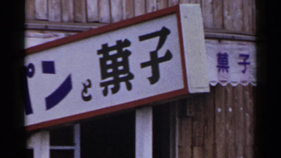 The final frame shows a cropped Japanese directional sign, striped awning and wooden exterior in 1953 Japan home-movie footage.