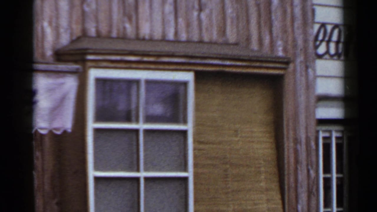 Wooden building facade with white-framed windows and partial storefront signage.