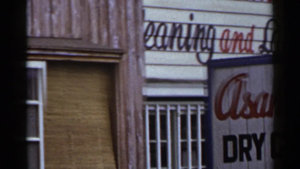 1953 Japan street facade with partial Asahi Laundry lettering, barred windows, wood siding, and white trim.