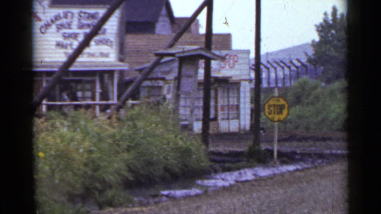 Weathered roadside storefront with faded shoe-repair sign and yellow stop sign.