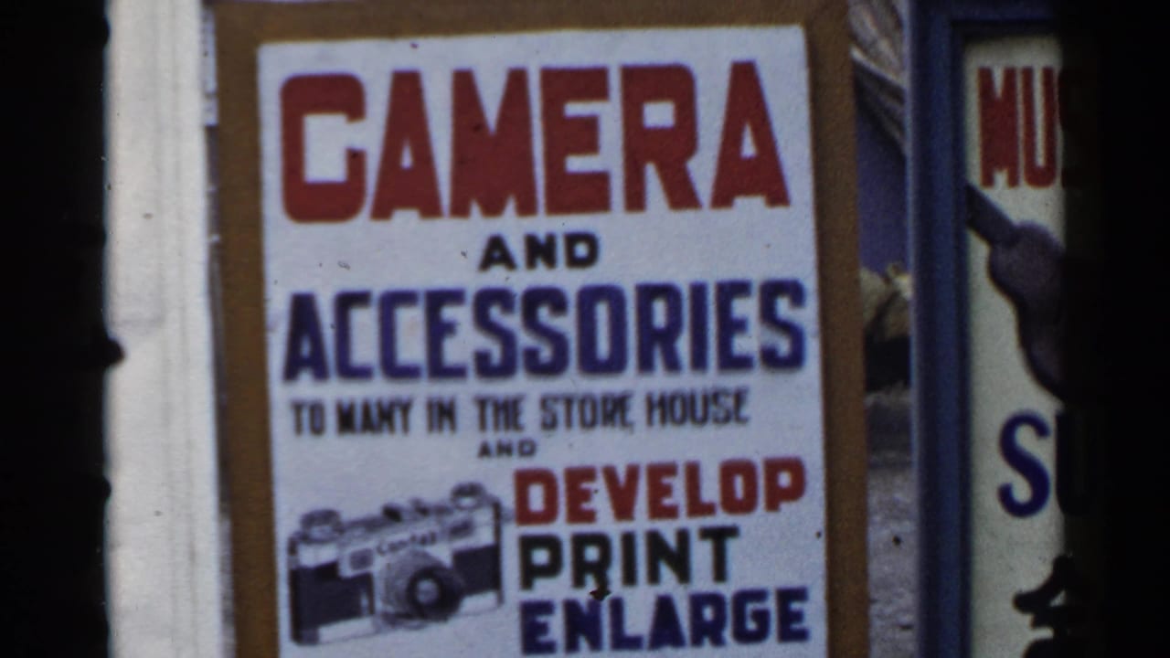 Close view of a camera and accessories sign with red and blue lettering.