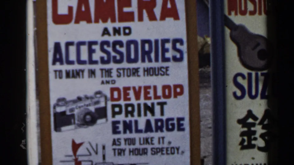 1953 Japan 8mm frame focusing lower on the camera advertisement, showing the service text and small camera graphic in soft handheld framing.
