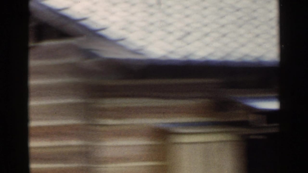 1953 Japan 8mm frame with a pale-roofed rural building passing close to the camera.