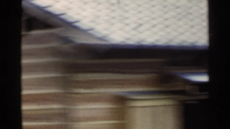 1953 Japan 8mm frame with a pale-roofed rural building passing close to the camera.