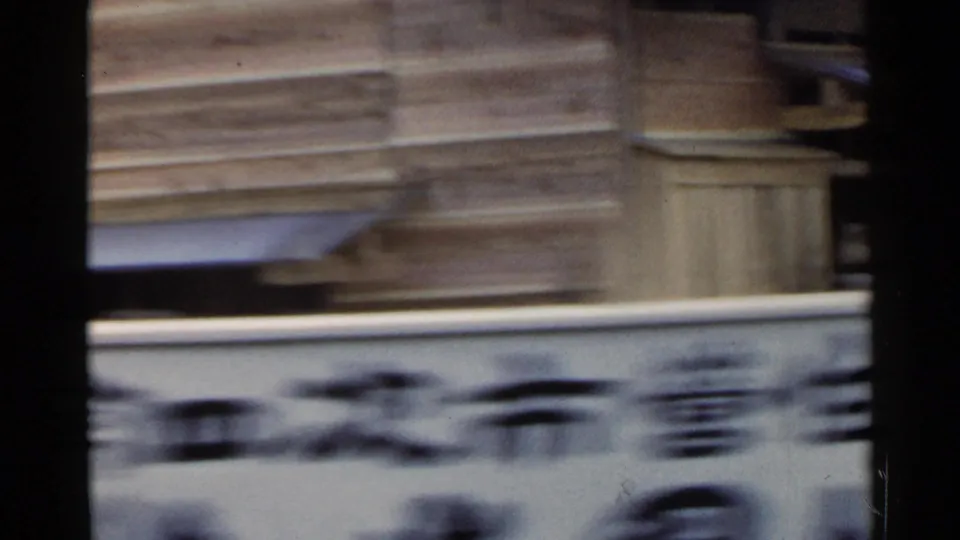 1953 Japan 8mm frame showing a blurred building wall and roofline with dark film-edge markings below.