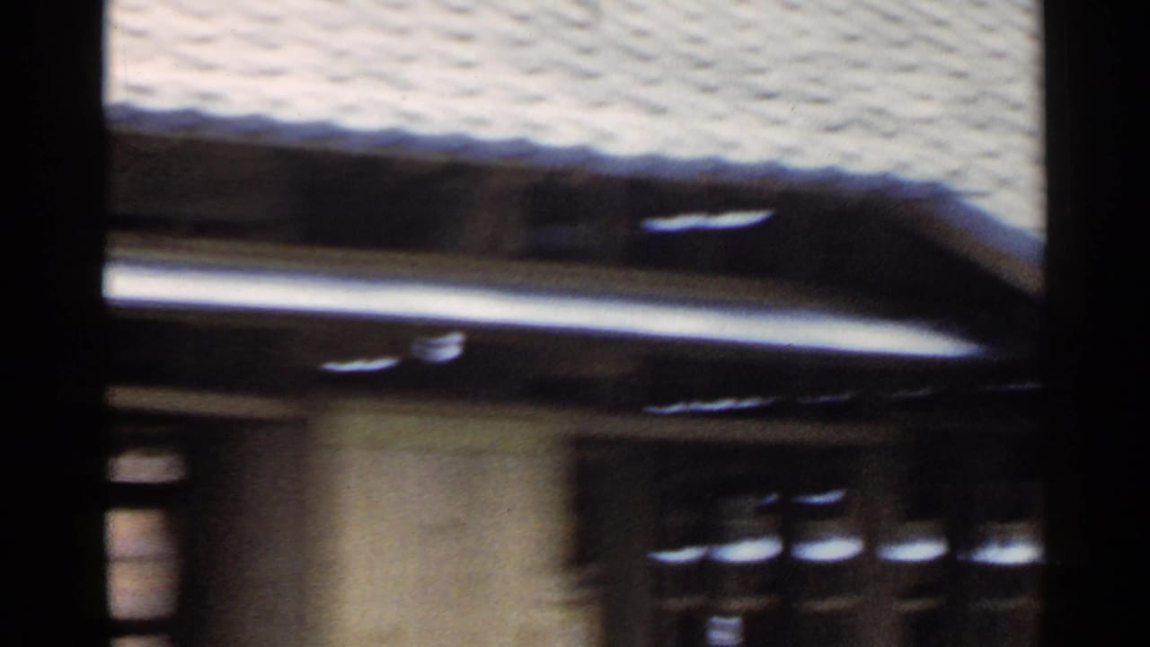 Blurred passing view of a tiled roof and wooden building facade.