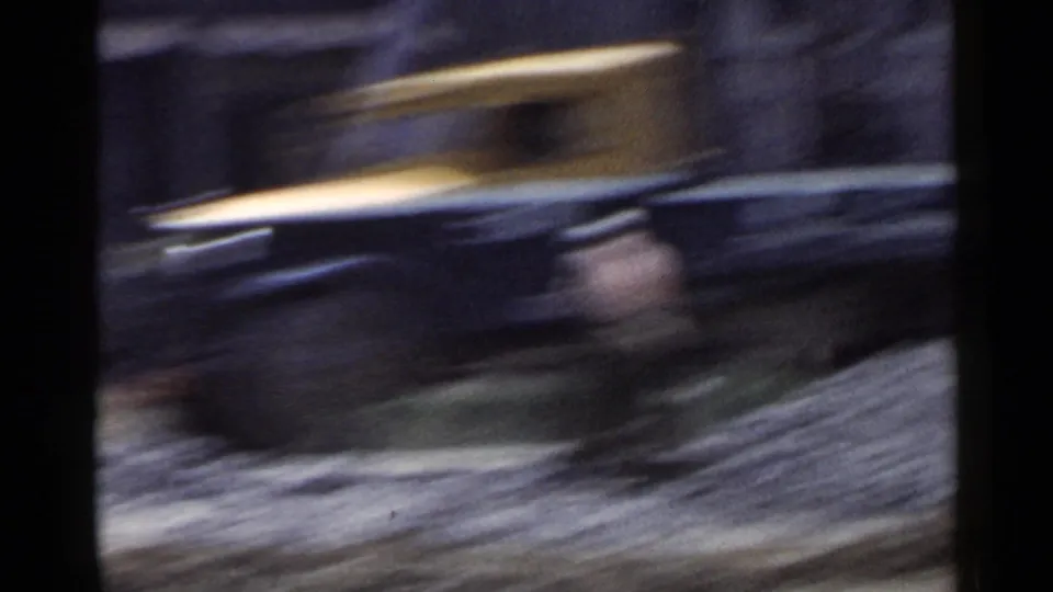 1953 Japan 8mm frame showing a blurred yellow roadside or vehicle shape beside darker forms during fast movement.