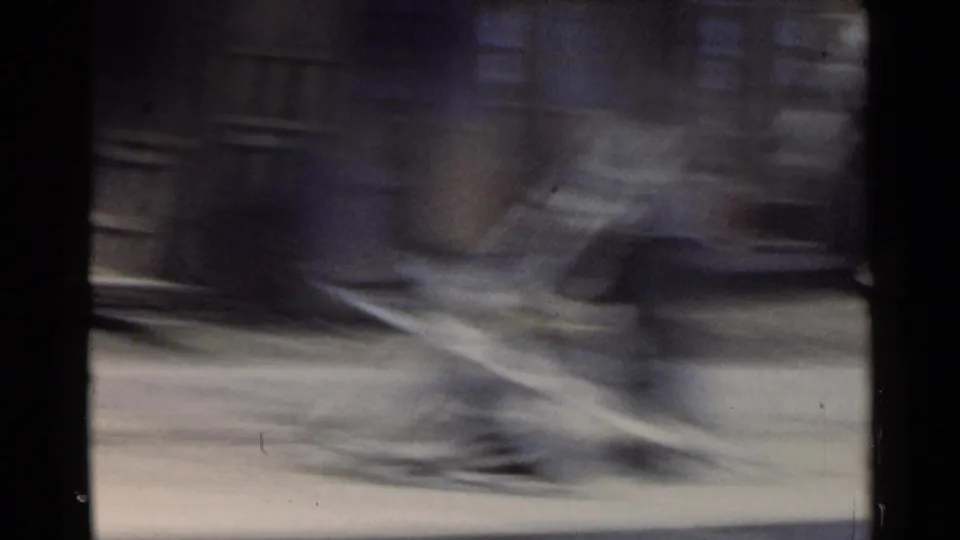 1953 Japan 8mm roadside view with a heavily blurred passing vehicle or object, pavement, and dark frame edges from a moving car.
