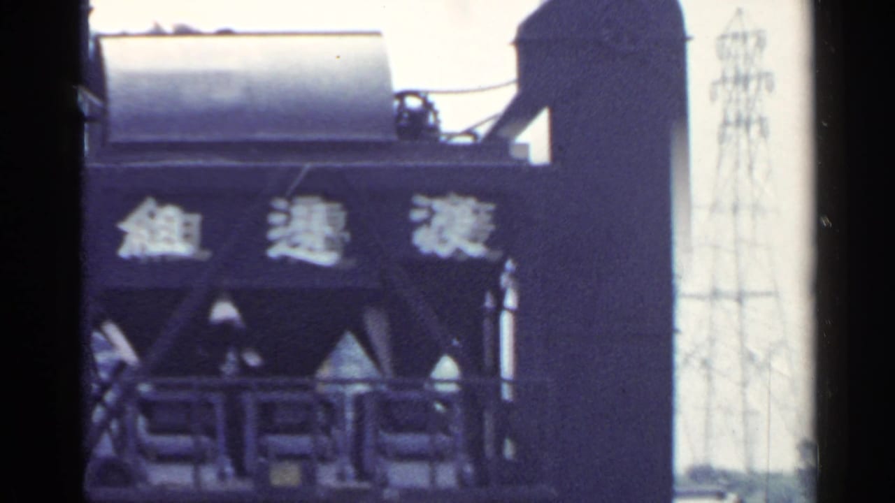 1953 Japan industrial scene showing a tall steel structure with Japanese characters and machinery details in soft 8mm color.