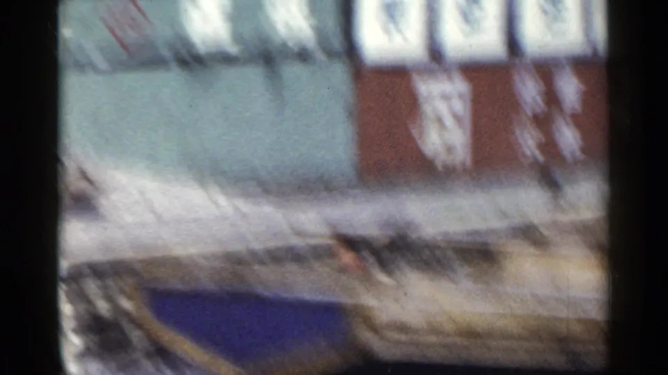 1953 Japan home-movie frame from a moving train, showing weathered walls with large Japanese characters and a low stone or curb edge.