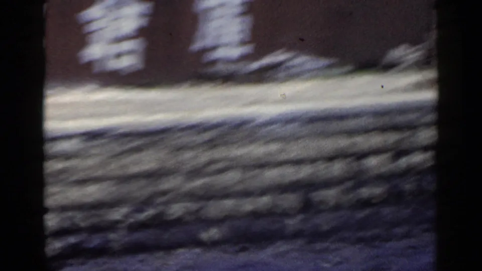1953 Japan train-window frame with white Japanese writing on a wall above rough stonework, softened by motion blur.