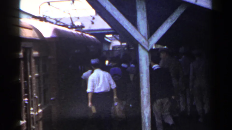 The final 1953 Japan station frame shows passengers walking away beside the train beneath wooden beams and overhead wires.