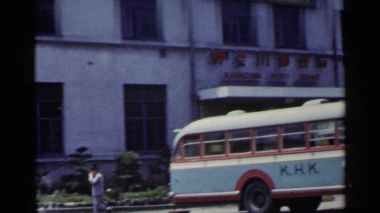 1953 Japan street frame with part of a K.H.K. bus, a pedestrian, and a civic-looking building facade.