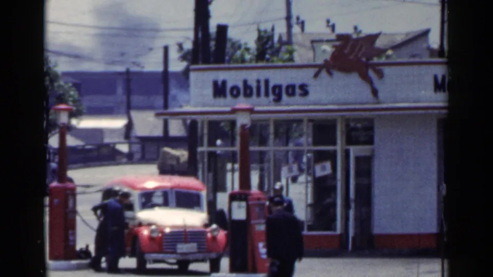 1953 Japan fuel-station view showing Mobilgas signage, Pegasus logo, red pumps, a car, and people near the forecourt.