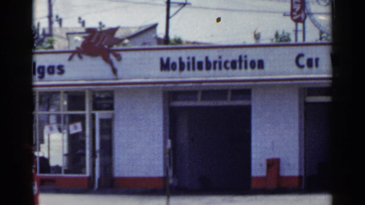 Mobilubrication sign over a service bay with partial Mobilgas lettering and street foreground.