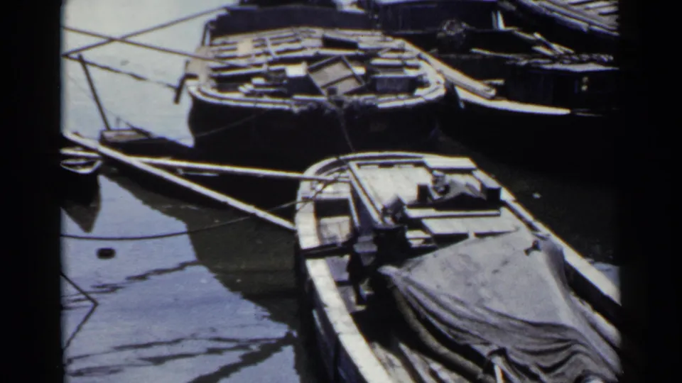 1953 Japan 8mm frame showing multiple small wooden boats moored together, including a foreground boat partly covered by a tarp.