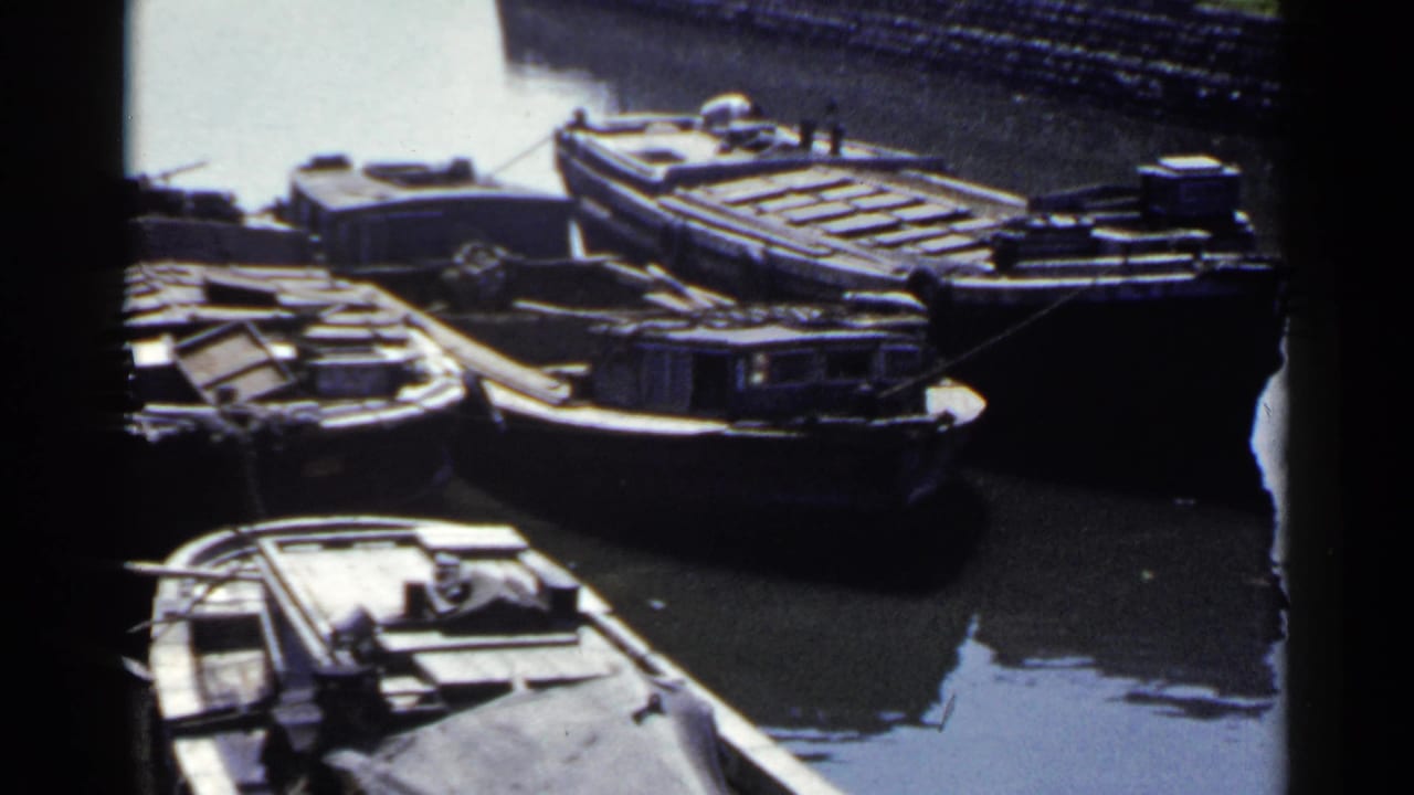Several moored barges and boats clustered beside a stone-lined waterway.