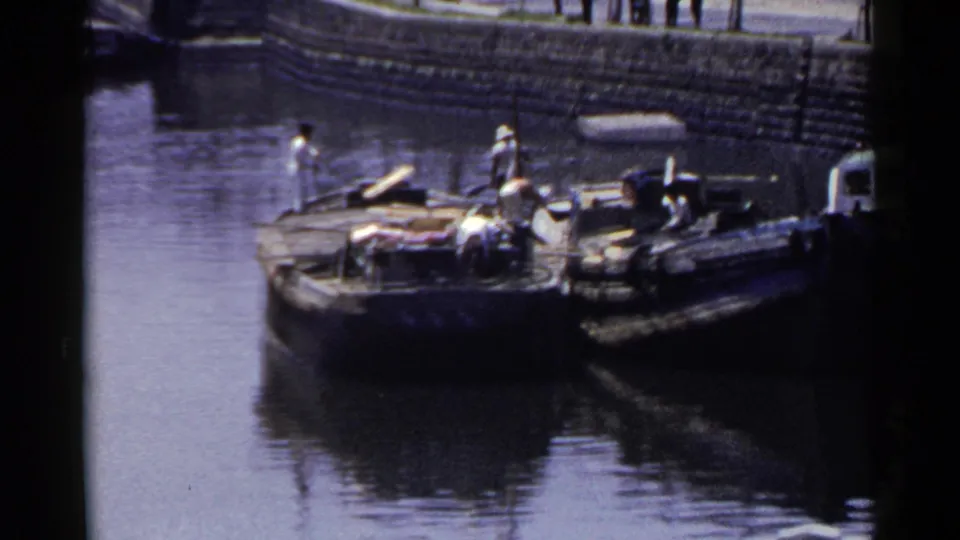 1953 Japan harbor boats lie moored together on reflective water, with people visible on the vessels.