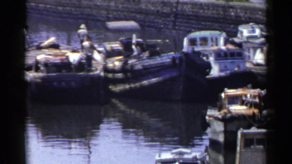 1953 Japan harbor scene showing several moored boats, people on deck, reflective water, and a small cabin boat.