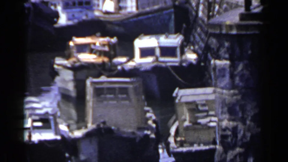 1953 Japan canal scene with compact working boats, small cabin tops, mooring lines, and a stone wall at the water's edge.