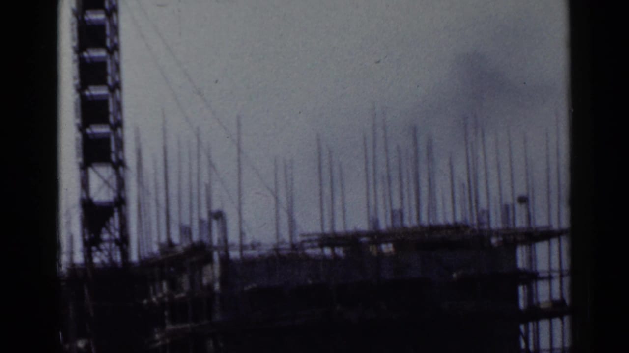 1953 Japan 8mm frame showing a tall scaffolded construction structure with vertical rods and dark film edge borders.