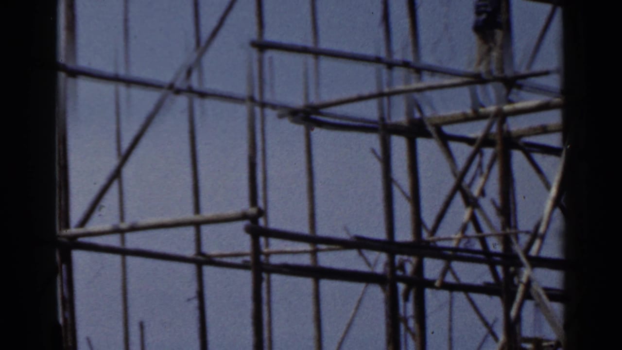 Worker standing high on scaffolding near the top edge of the frame.