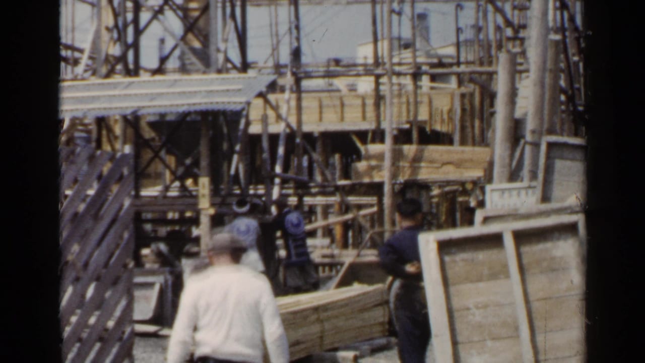 Workers move near wooden planks and scaffolding at a construction site.