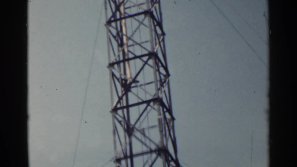 1953 Japan frame showing the tower's midsection with cross-braced steel members, guy wires, and soft home-movie color.