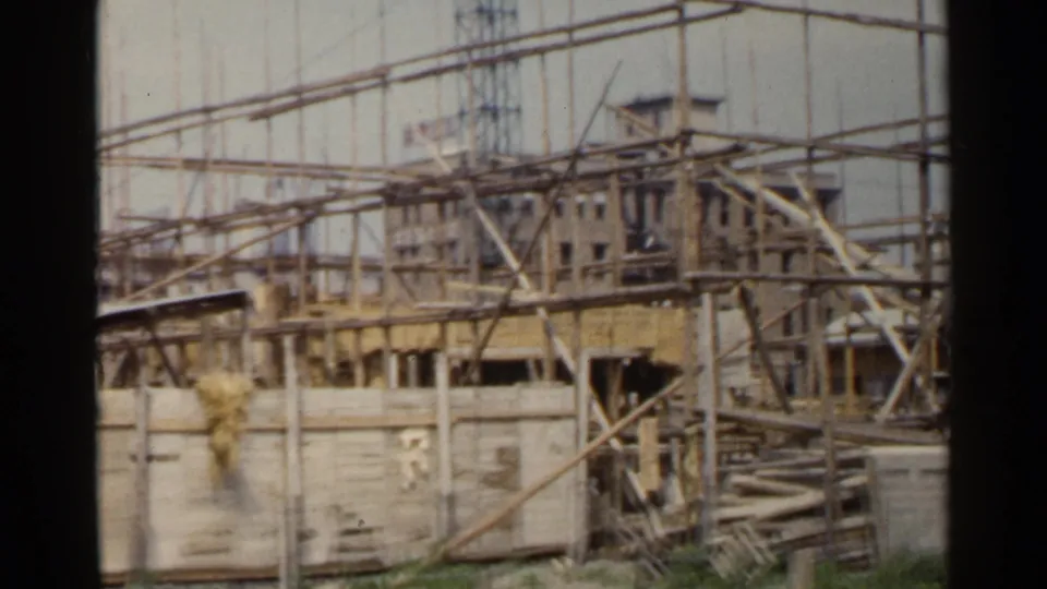1953 Japan 8mm frame showing wooden scaffolding around a partially constructed building.