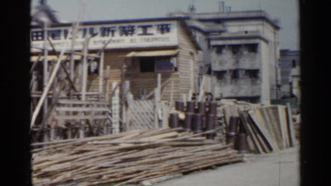 Construction site with scaffolding, Japanese signage, stacked lumber, and building materials.