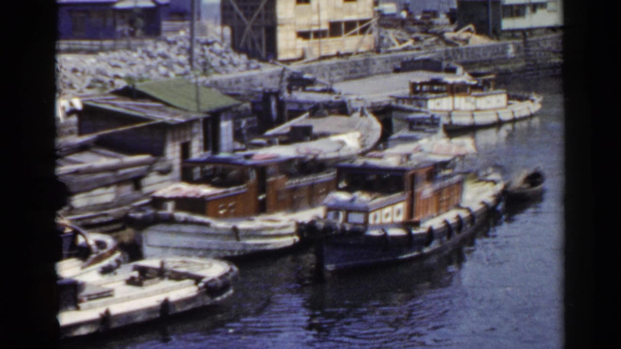 Small wooden boats moored along a narrow waterway with buildings behind them.
