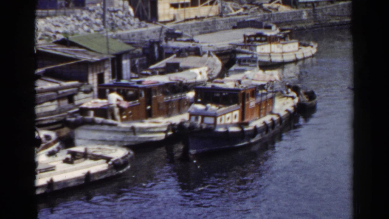 Docked boats clustered near a quay as a man stands on one deck.
