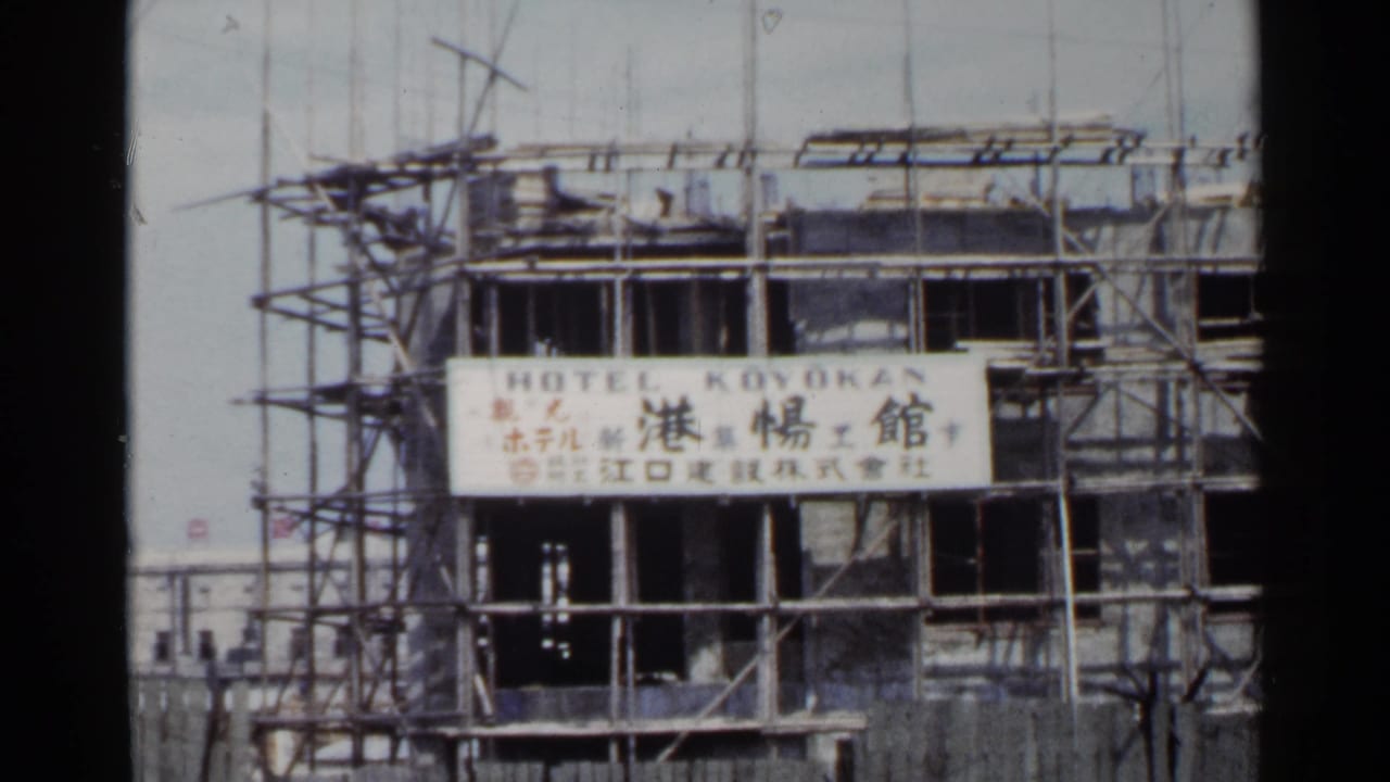 1953 Japan home-movie frame of scaffolding around an unfinished hotel facade with Hotel Koyokan lettering and Japanese text.